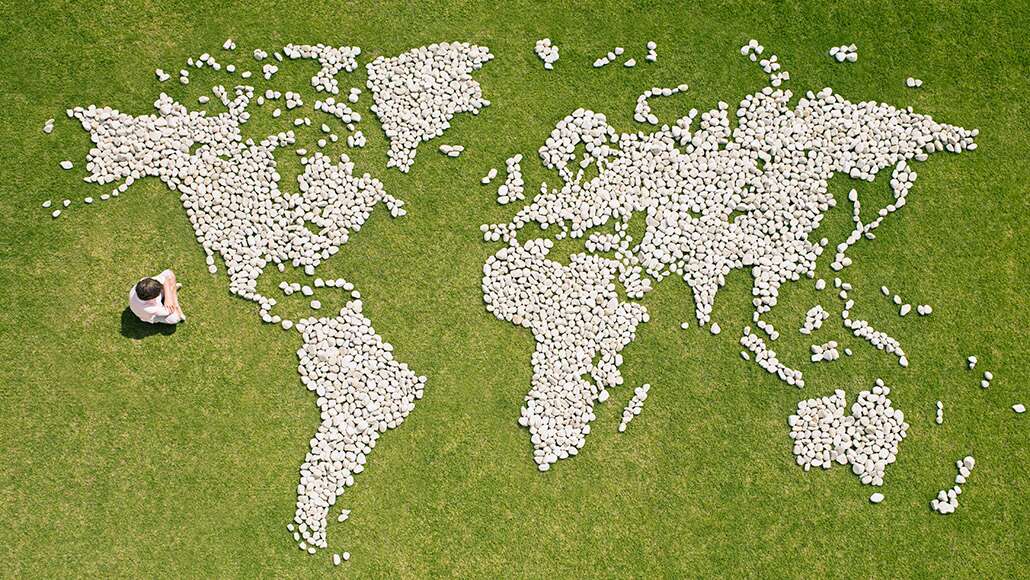 A boy sitting in front of a world map made from stones