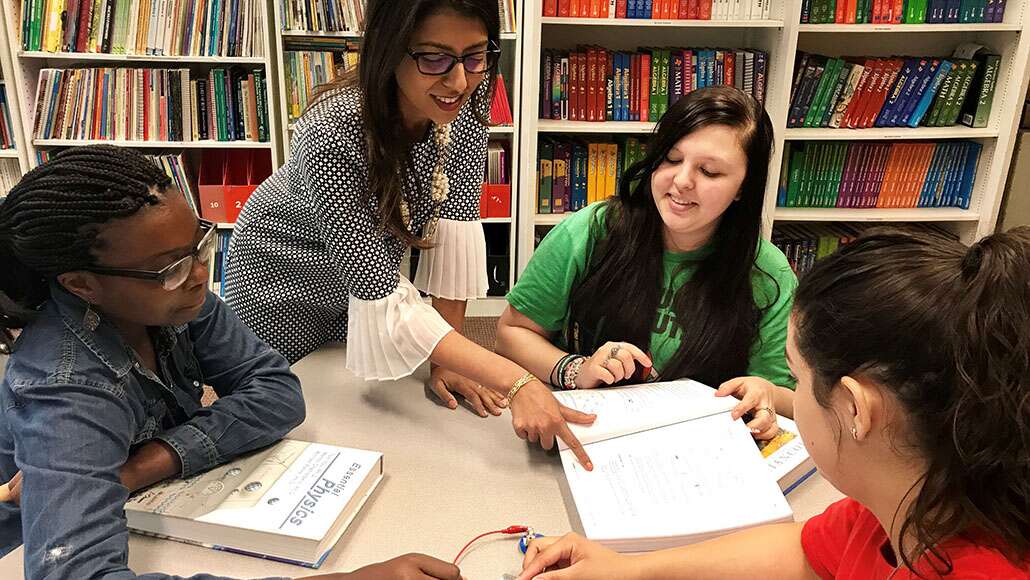 A female teacher teaching three young girls