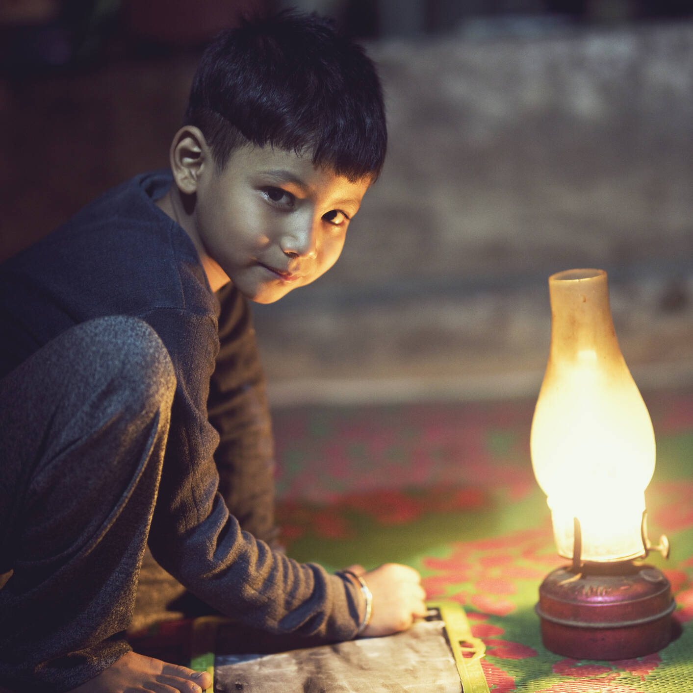 young boy with chalkboard illuminated by oil lamp