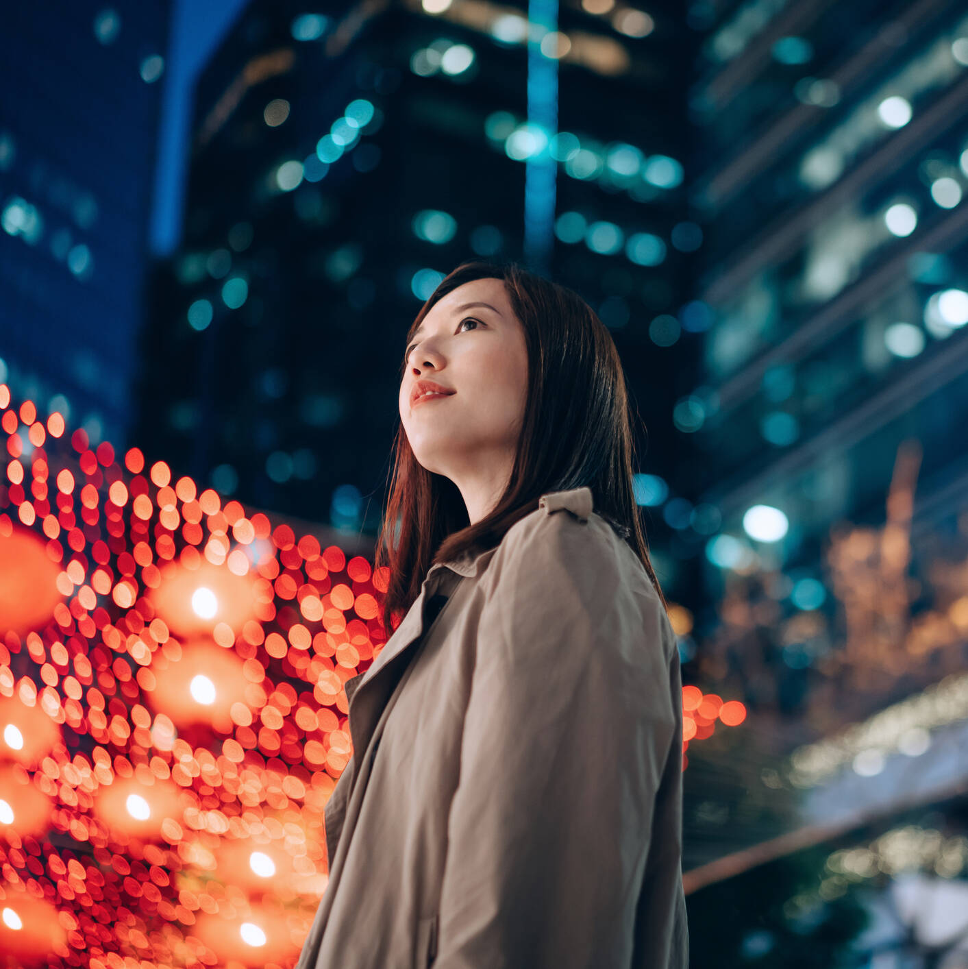 Asian woman in front of city lights at night. 