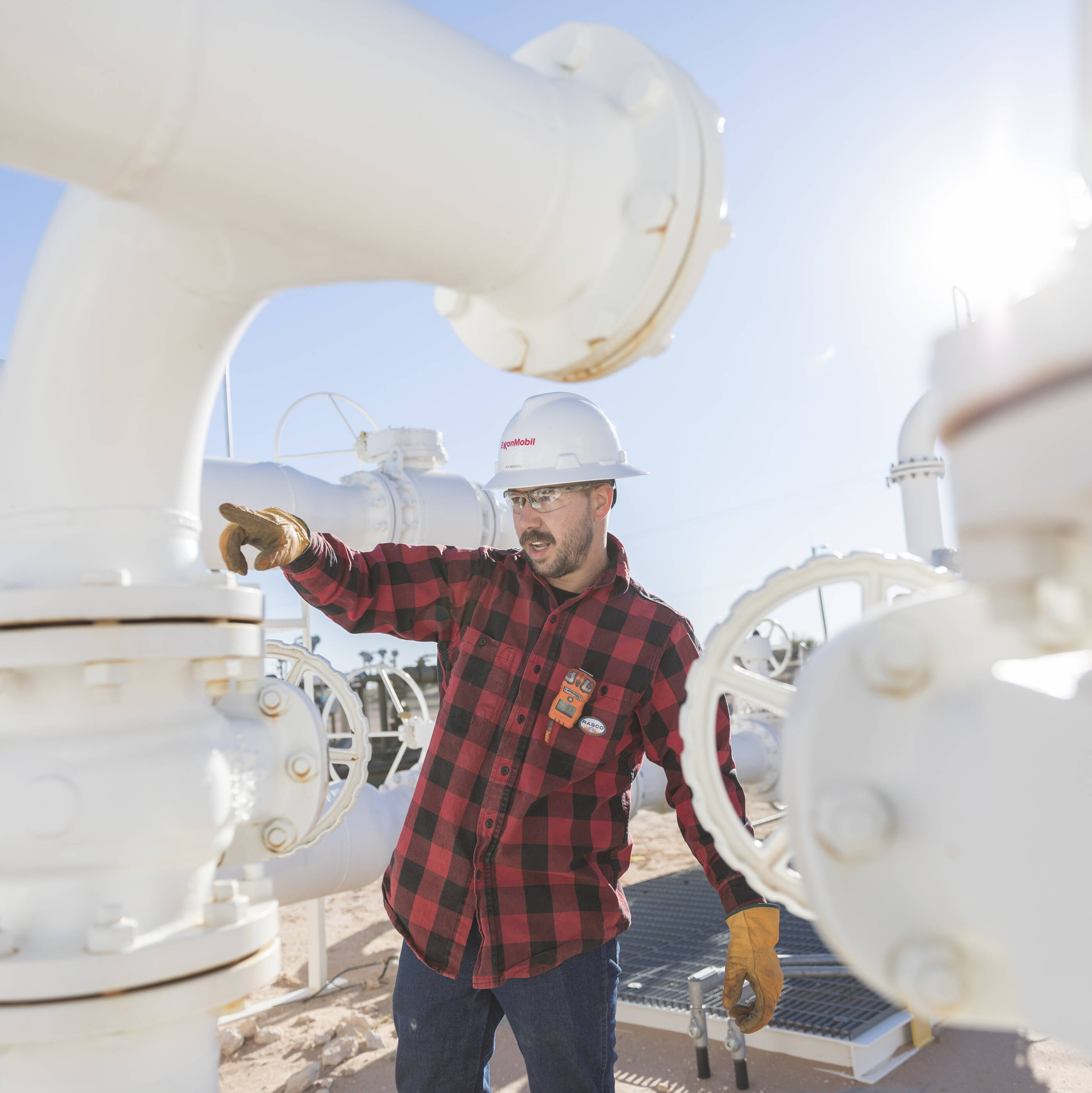 ExxonMobil employee working on a plant surrounded by pipes.