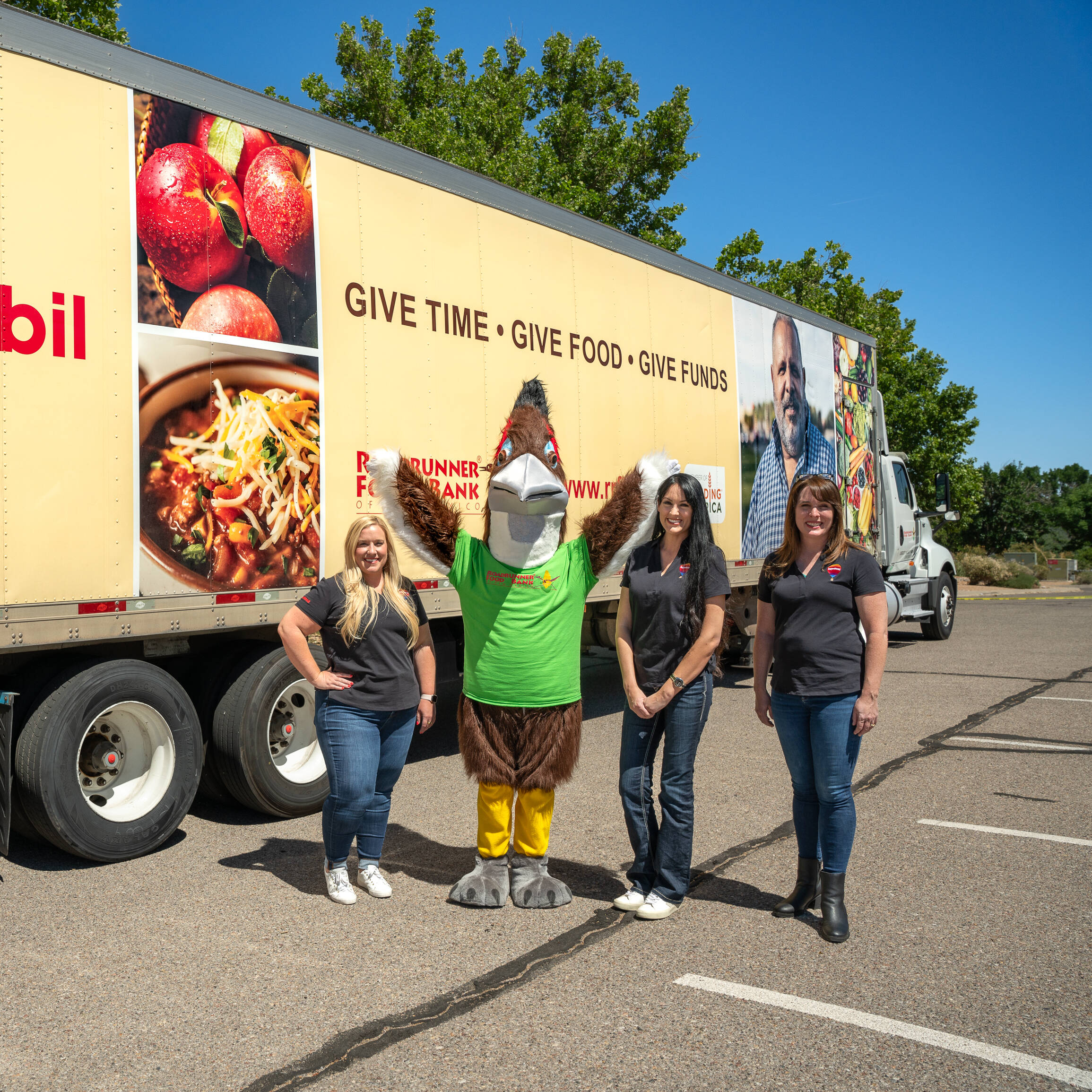 ExxonMobil employees with a mascot in front of a semi-truck full of food donations.