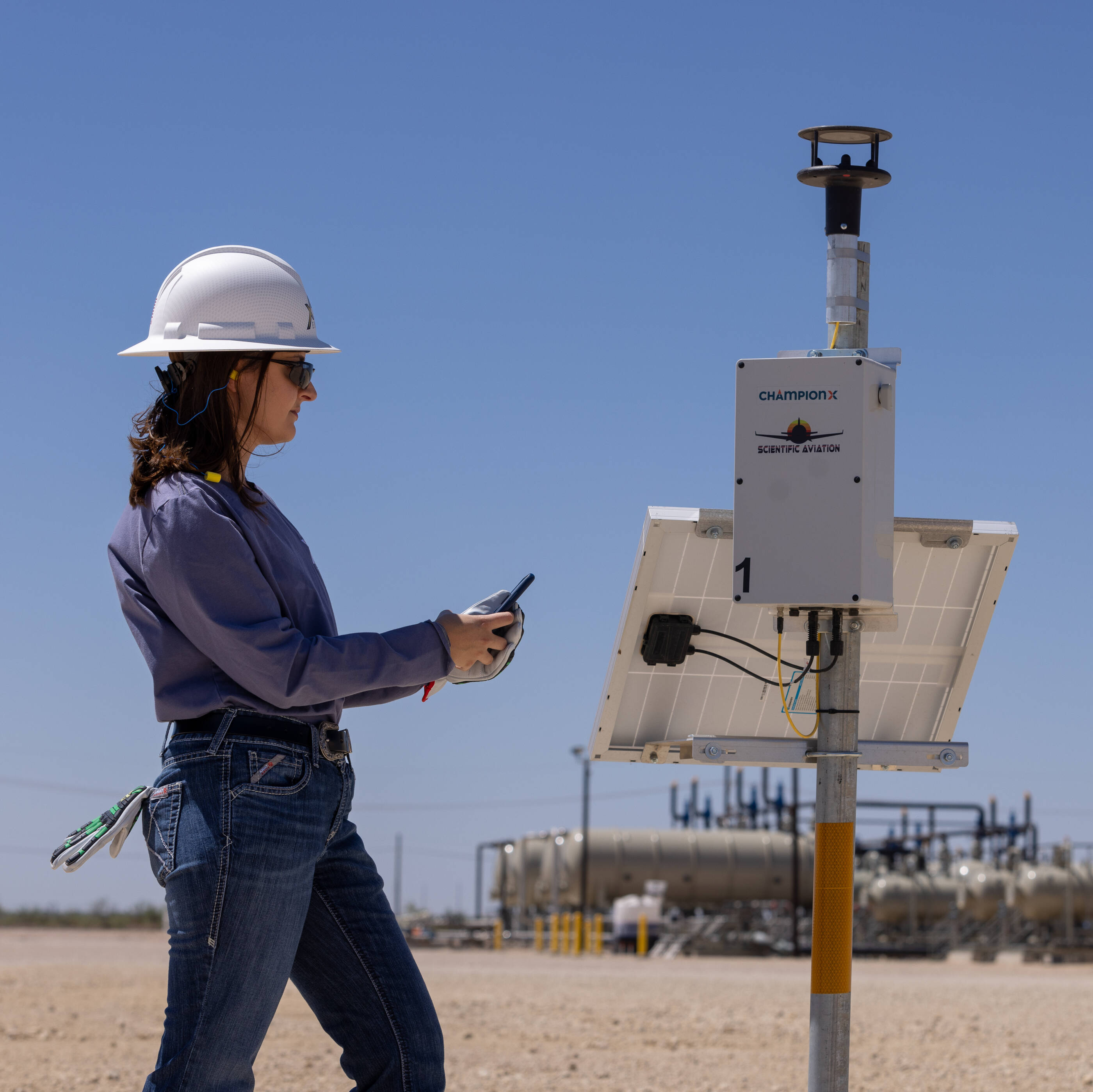 Woman in hard hat using technology for XTO operations in the Permian Basin