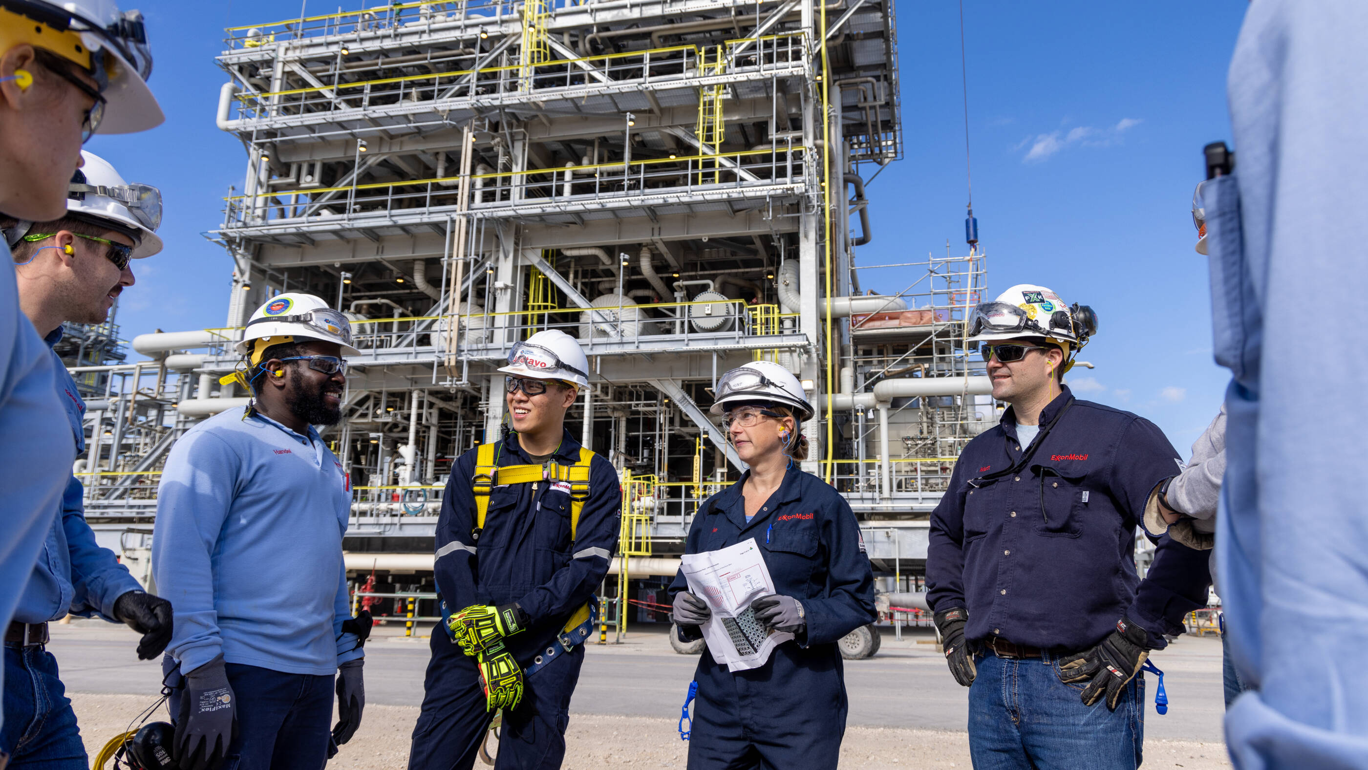 ExxonMobil team standing outside an oil rig talking.