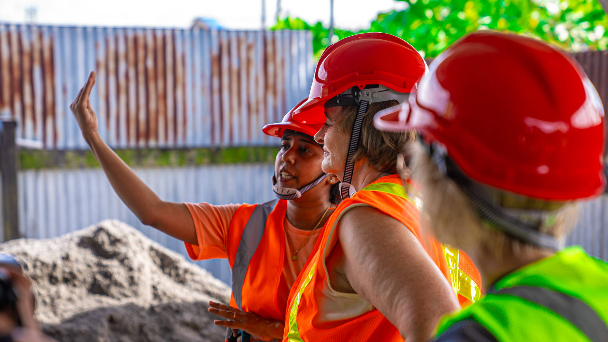 Women working and planning in a plant with hard hats on.