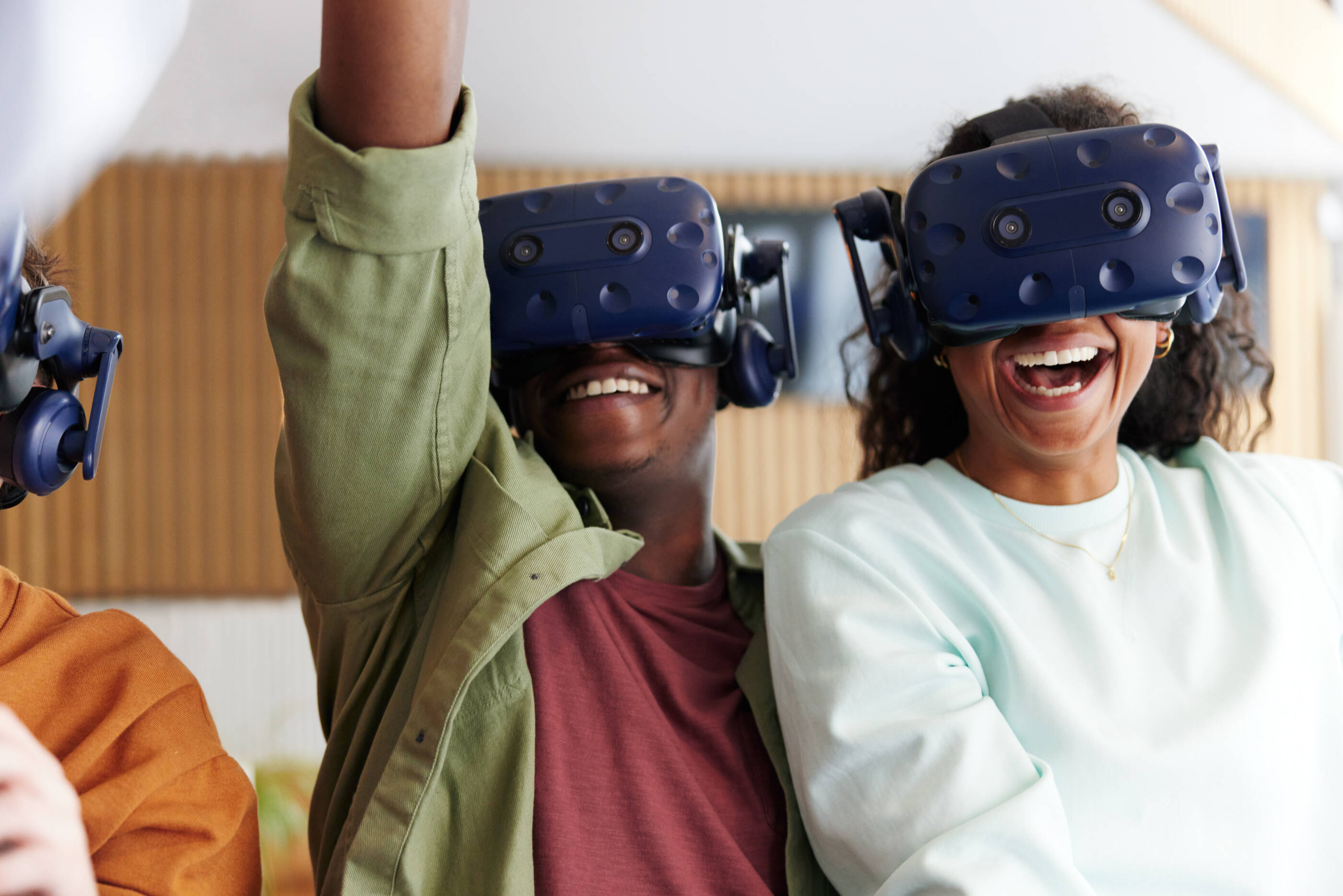 Diverse group of laughing young teenage friends wearing vr headsets to explore an interactive world at a vr club